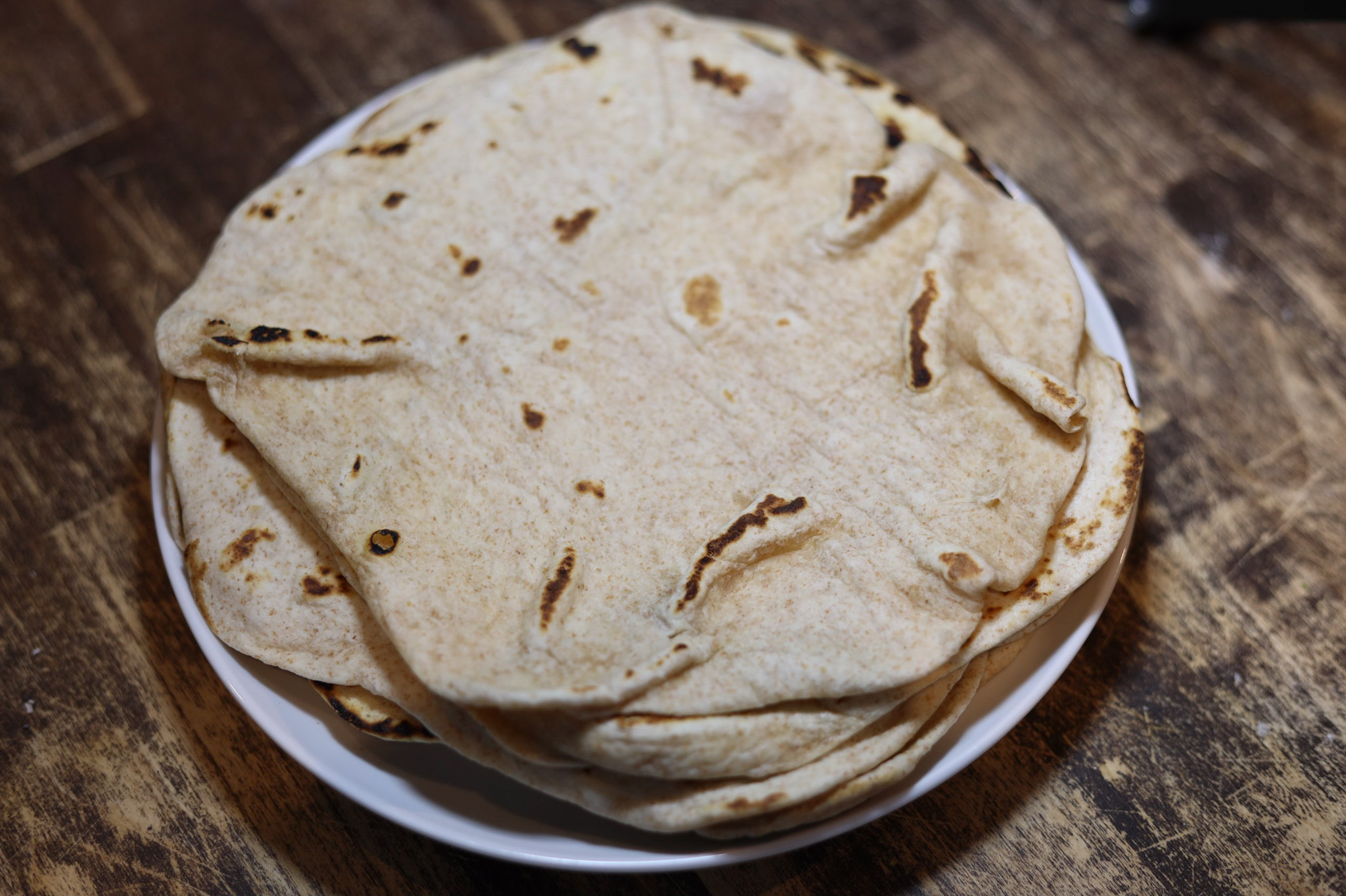 Sourdough flour tortillas sit on a white plate ready to eat